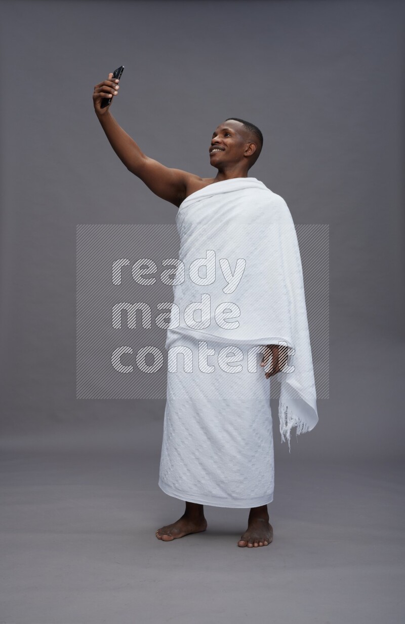 A man wearing Ehram Standing taking selfie on gray background