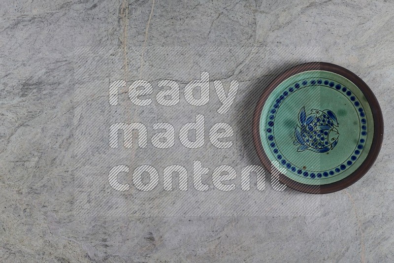 Top View Shot Of A Decorative Pottery Plate On Grey Marble Flooring