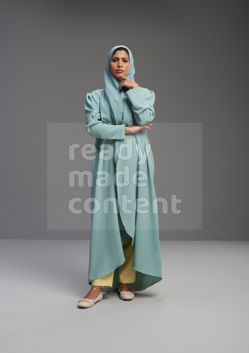 Saudi Woman wearing Abaya standing interacting with the camera on Gray background