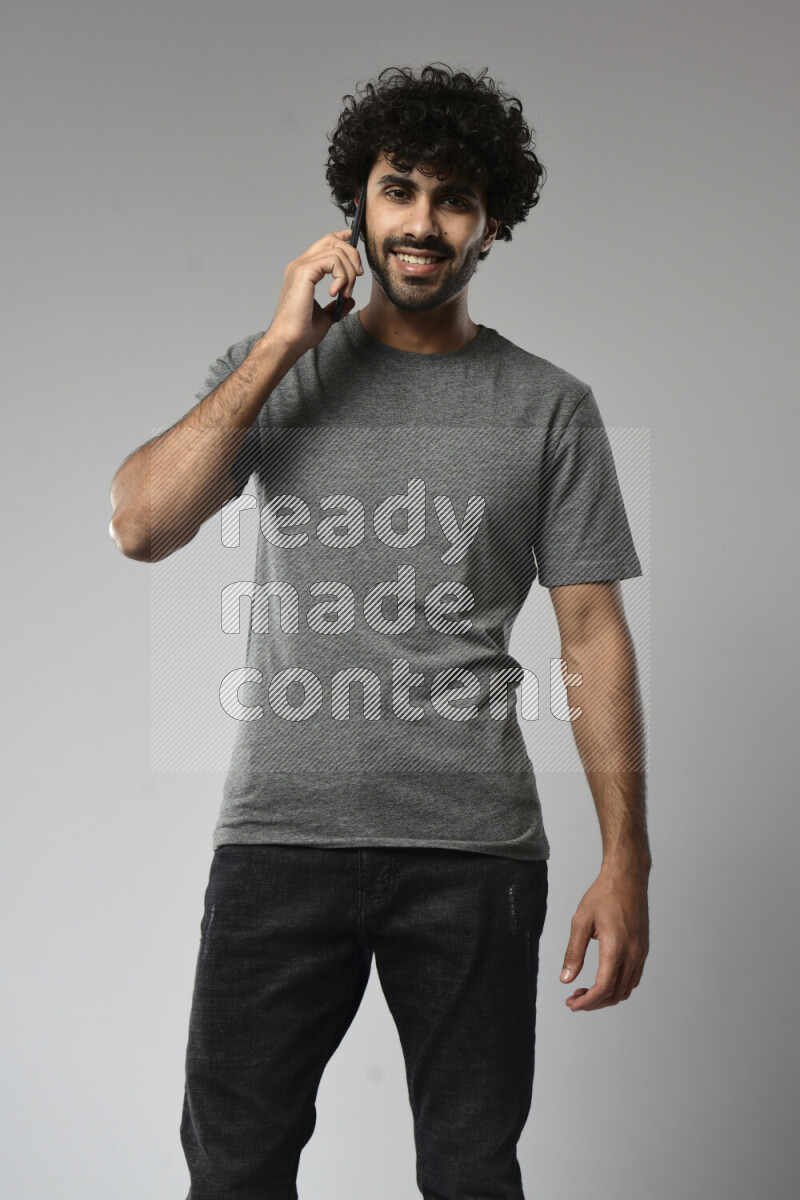 A man wearing casual standing and talking on the phone on white background