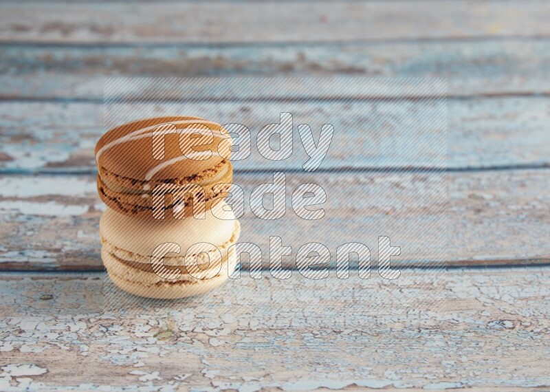45º Shot of of two assorted Brown Irish Cream, and White Caramel fleur de sel macarons on light blue background