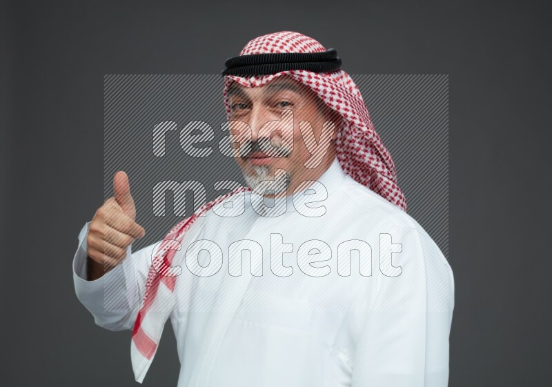 Saudi man with shomag Standing Interacting with the camera on gray background