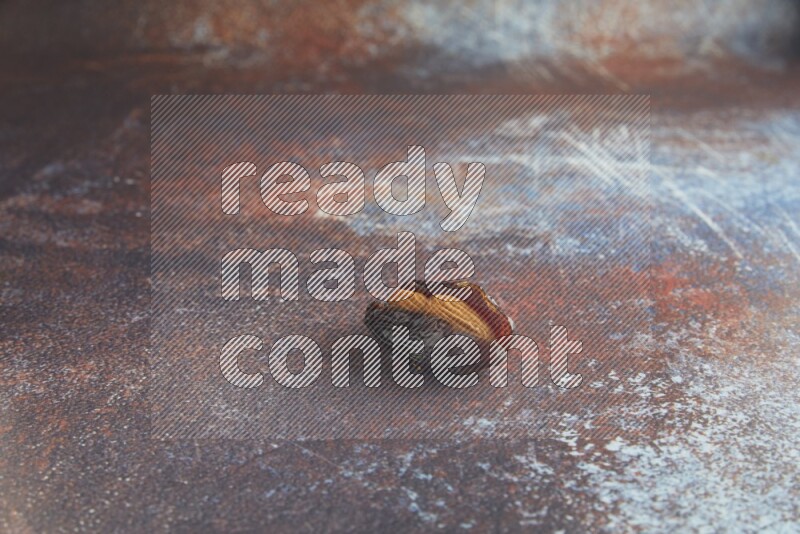 one almond stuffed madjoul date on a rustic reddish background