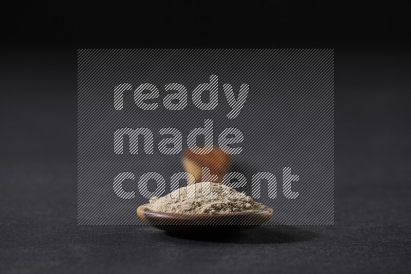 ملعقة خشبية كبيرة مليئة ببودرة الثوم على خلفية سوداء