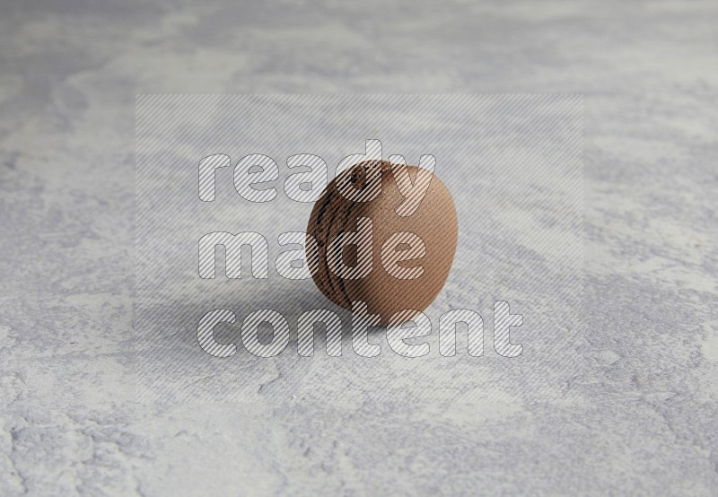 45º Shot of Brown Dark Chocolate macaron on white  marble background