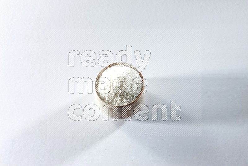 A beige ceramic bowl full of desiccated coconut on a white background in different angles