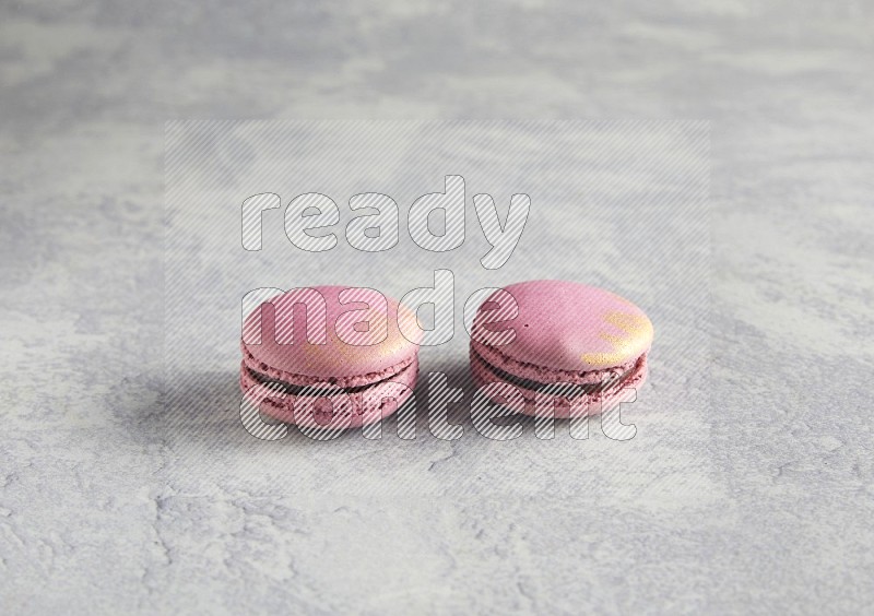 45º Shot of two Purple Strawberry macarons on white  marble background