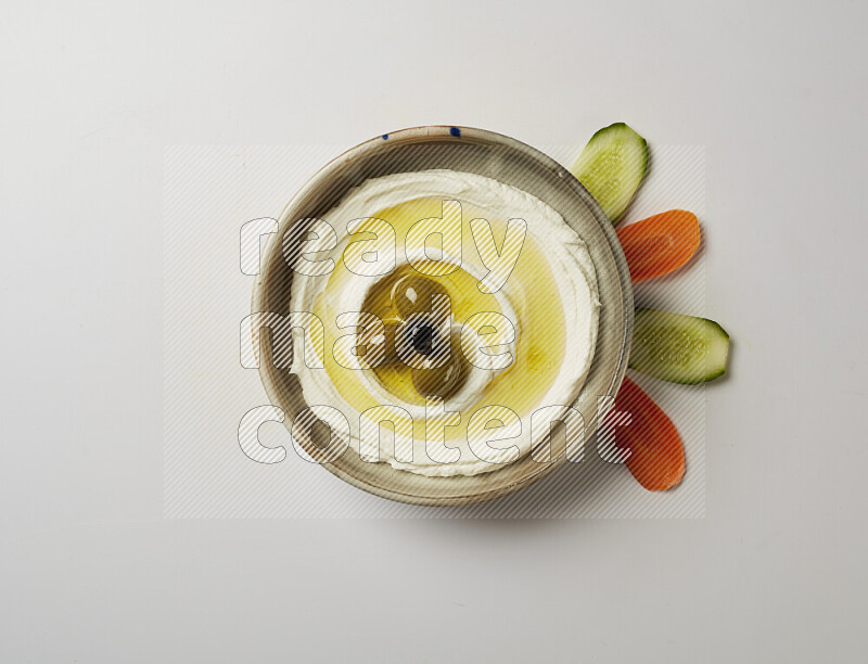Lebnah garnished with whole olives in a grey pottery plate on a white background