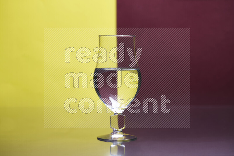 تظهر الصورة أواني زجاجية ممتلئة بالماء موضوعة على خلفية من اللونين الأصفر والأحمر الغامق