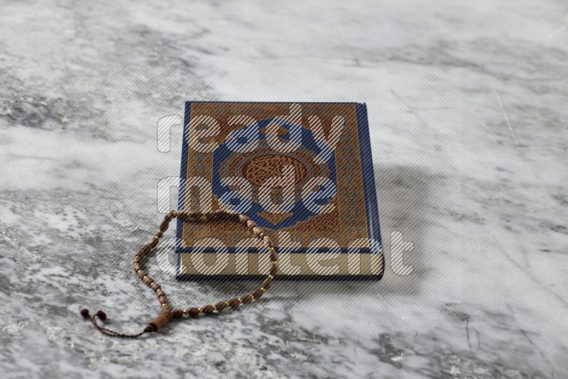 Quran with a prayer beads on grey marble background