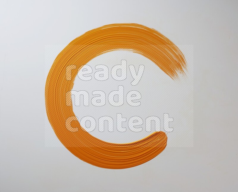 An orange circular painting brush stroke on white background