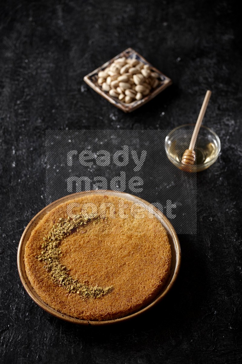 Konafa with nuts and honey in a dark setup