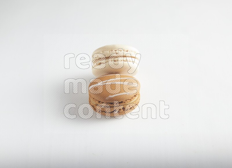 45º Shot of of two assorted Brown Irish Cream, and White Caramel fleur de sel macarons on white background