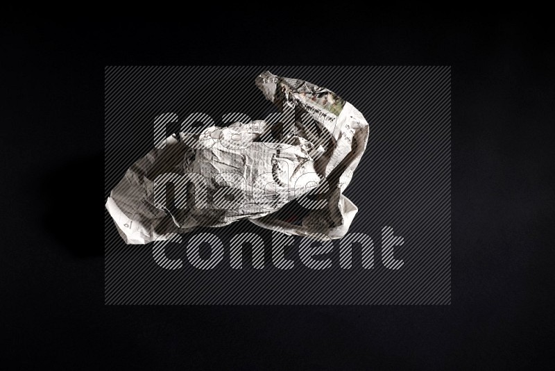 Crumpled newspaper sheet on black background