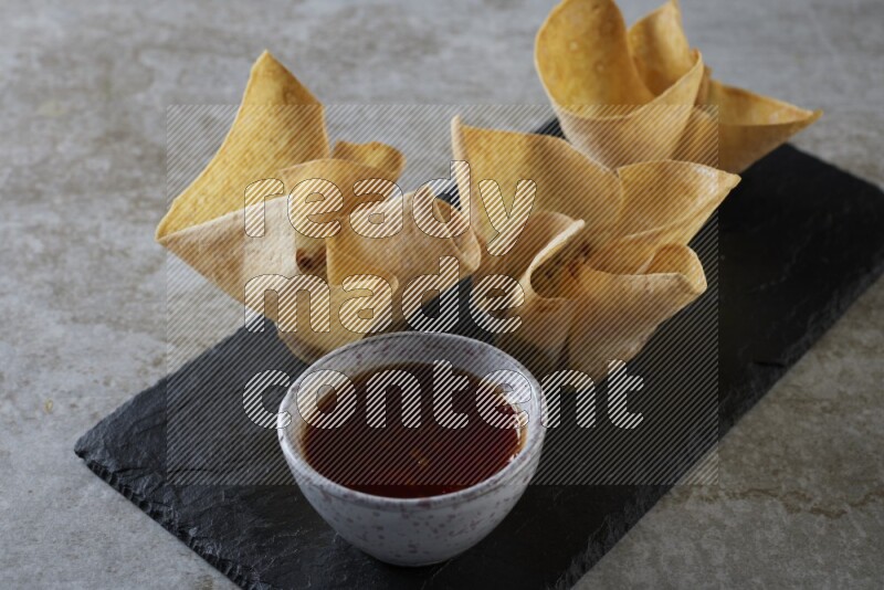 wonton cups with soy sauce ramkin on rectangle slate on grey textured counter top