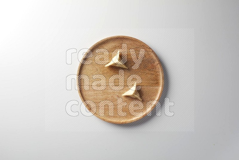 Two Sambosas on a wooden round plate on a white background