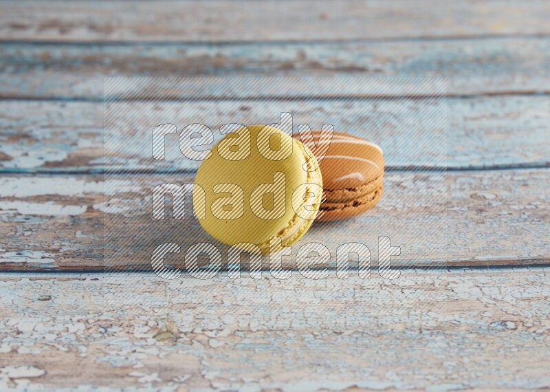 45º Shot of of two assorted Brown Irish Cream, and Yellow Lime macarons on light blue background