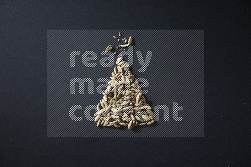 Cardamom in a triangle shape on black flooring