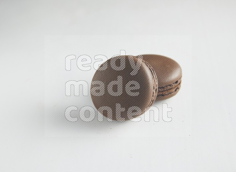 45º Shot of two Brown Dark Chocolate macarons on white background