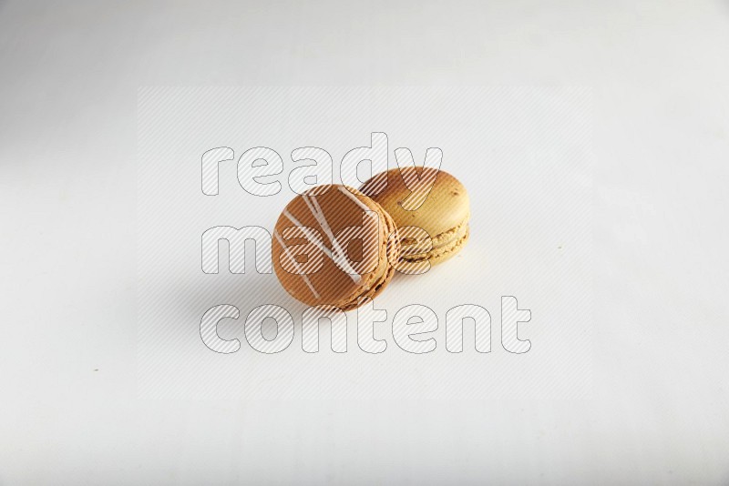 45º Shot of of two assorted Brown Irish Cream, and Yellow Crème Brulée macarons on white background