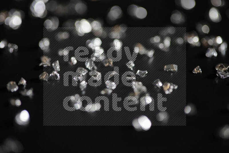 قطع زجاجية فضية لامعة متناثرة على خلفية سوداء