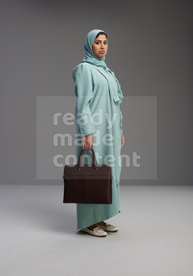 Saudi Woman wearing Abaya standing holding bag on Gray background