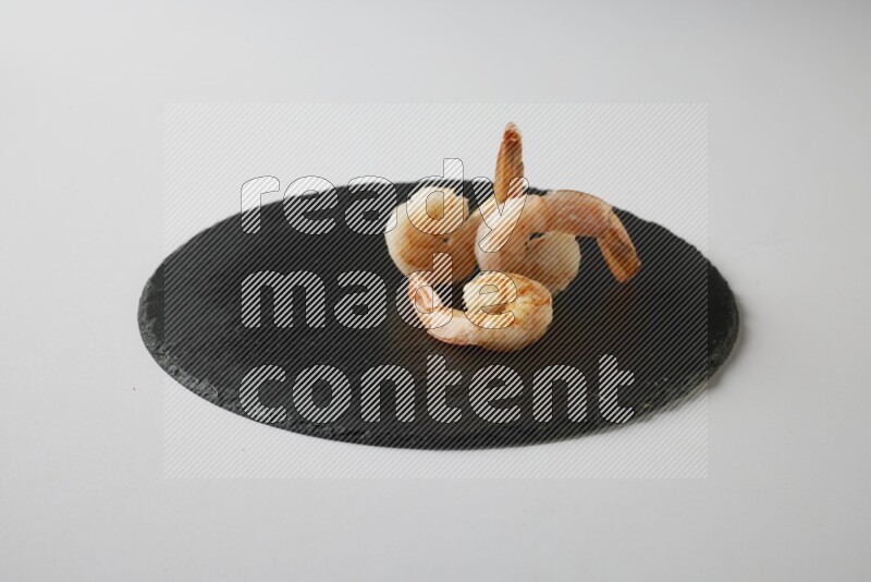 three grilled shrimp  on a black slate direct  on a white back ground