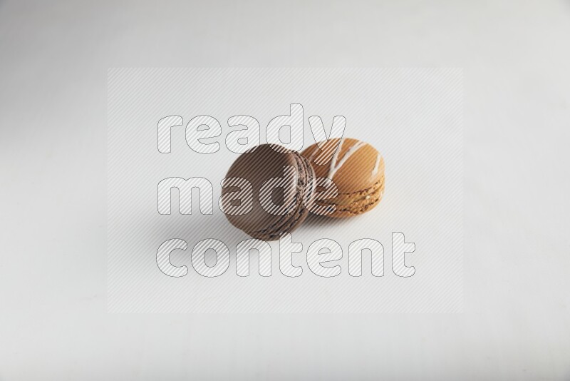 45º Shot of of two assorted Brown Irish Cream, and Brown Dark Chocolate macarons on white background