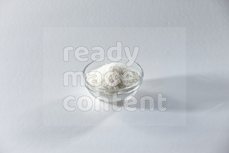 A glass bowl full of desiccated coconut on a white background in different angles