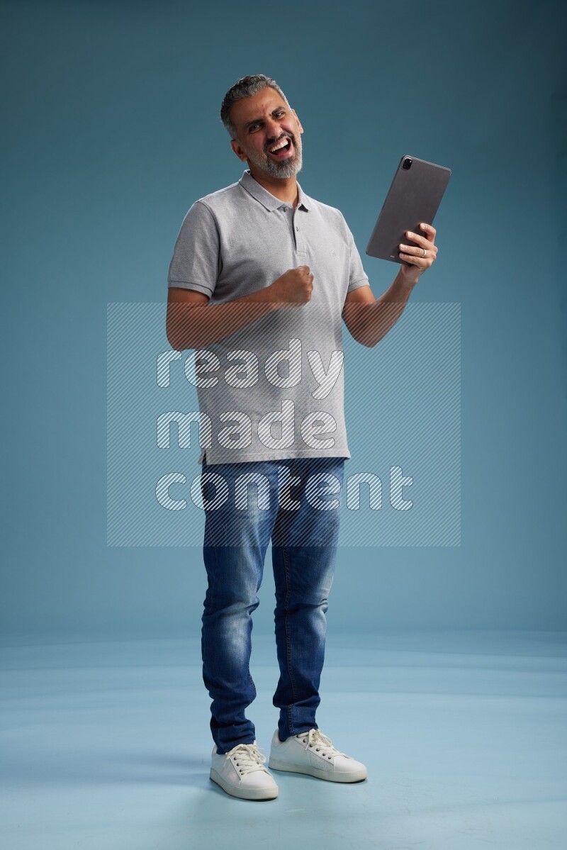 Man Standing working on tablet on blue background