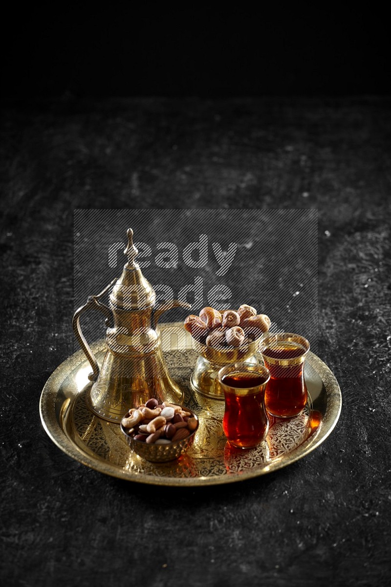 Nuts with dates and a drink on a metal tray in a dark setup