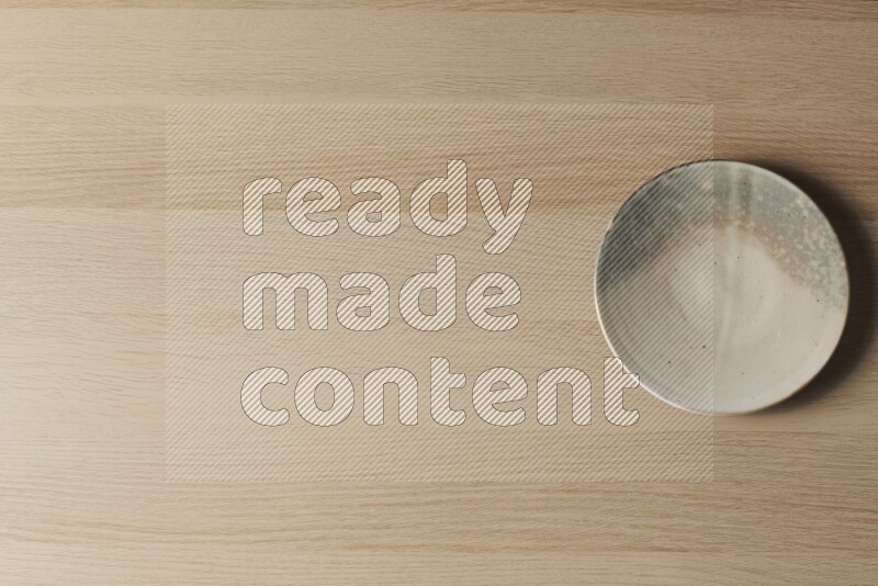 صحن فخاري متعدد الألوان على خلفية خشبية فاتحة