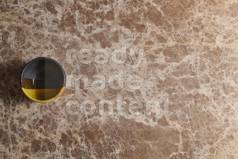 A multicolored pottery bowl on beige marble background