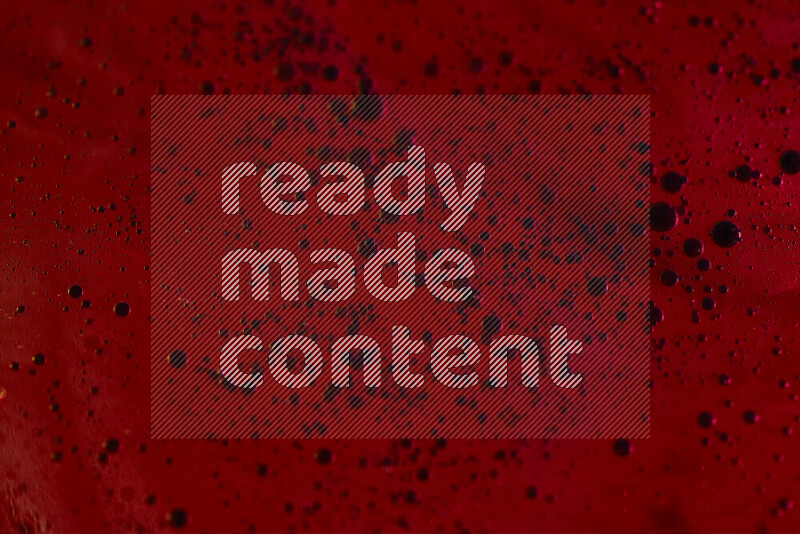 Close-ups of abstract blue watercolor drops on oil Surface on red background