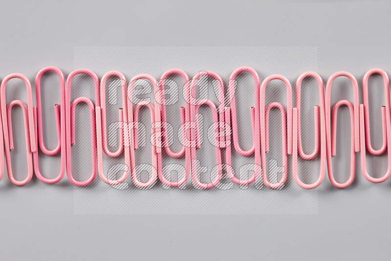 Pink paperclips isolated on a grey background