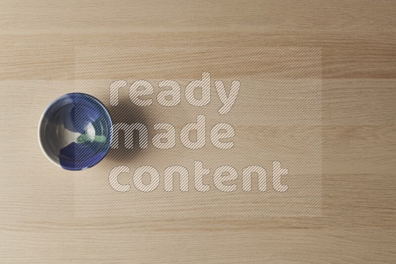 وعاء فخاري متعدد الألوان على خلفية خشبية فاتحة