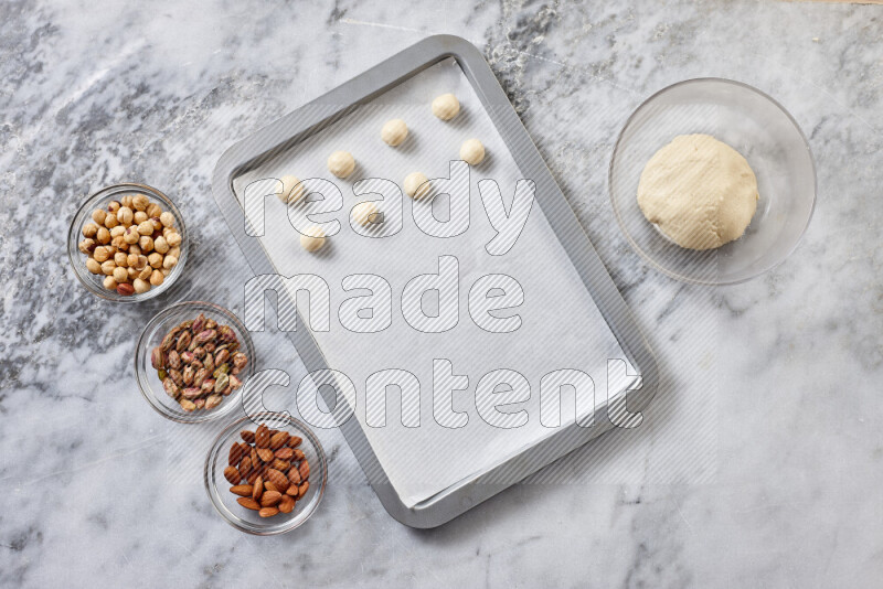 Ghoriba step by step with its ingredient, flour, powdered sugar, ghee and nuts on grey marble background