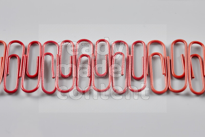 Red paper clips isolated on a grey background