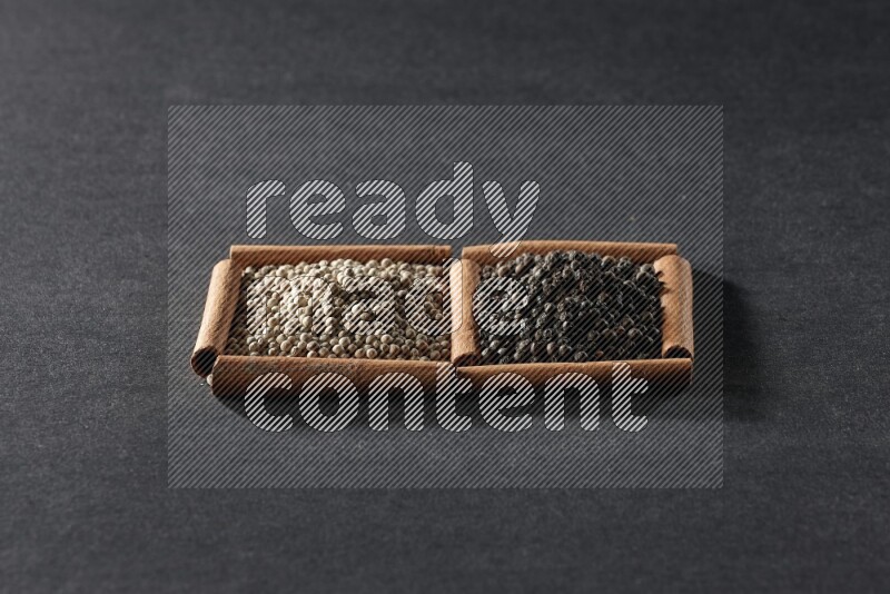 2 squares of cinnamon sticks full of white peppers and black peppers on black flooring