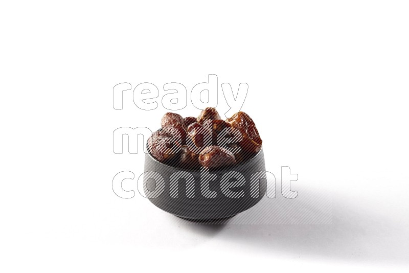 Dates in a black pottery bowl on white background