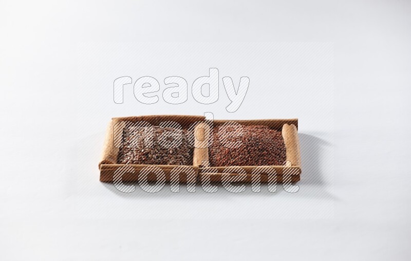 مربعان من أعواد القرفة ممتلئان ببذور الكتان وحب الرشاد علي خلفية بيضاء