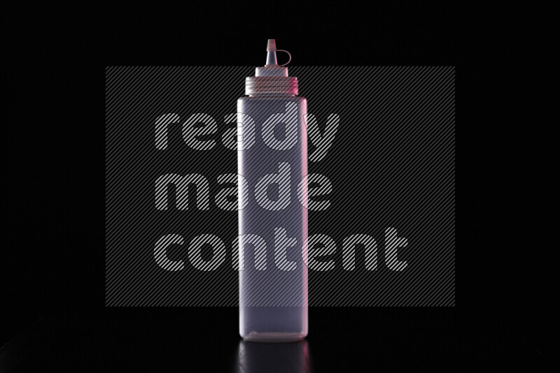 A squeeze bottle with colored rim light against black background