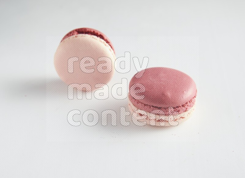 45º Shot of two Pink Litchi Raspberry macarons on white background