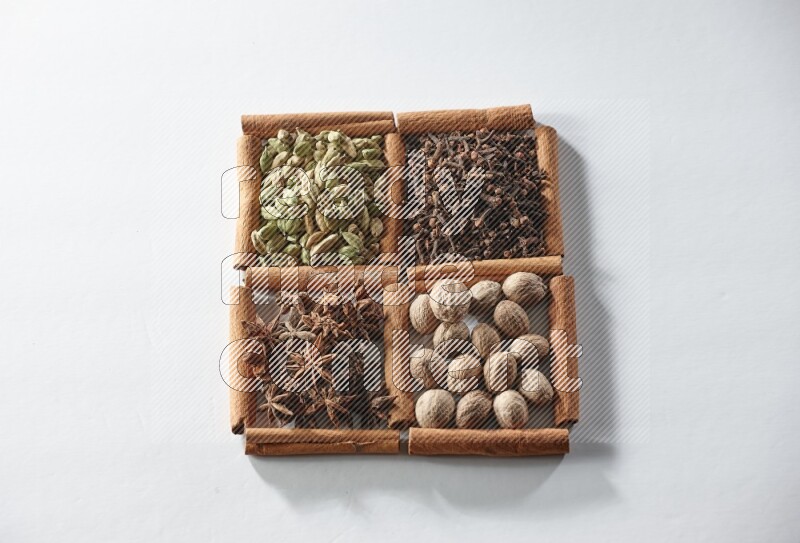 4 squares of cinnamon sticks full of cardamom, star anise, cloves and nutmeg on white flooring