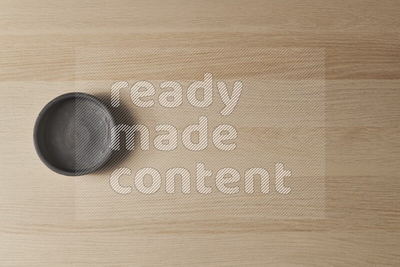 A black pottery bowl on light wooden background