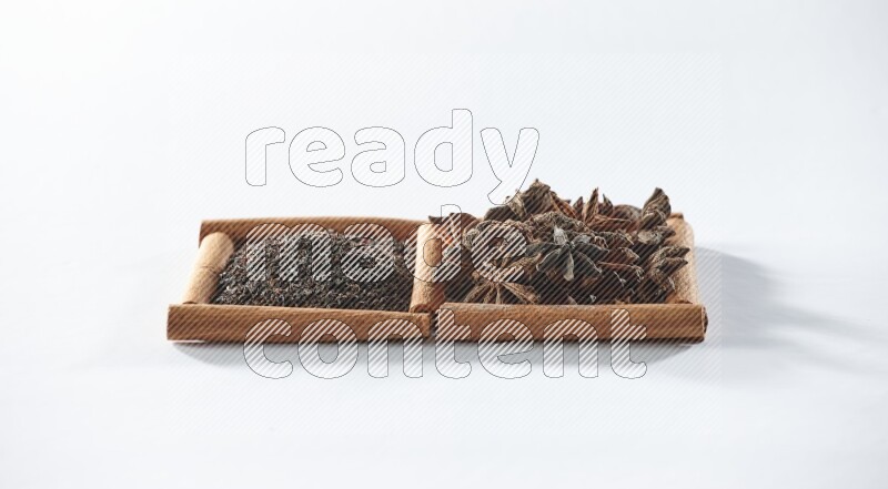 مربعان من أعواد القرفة ممتلئان بالشاي الأسود واليانسون النجمي علي خلفية بيضاء