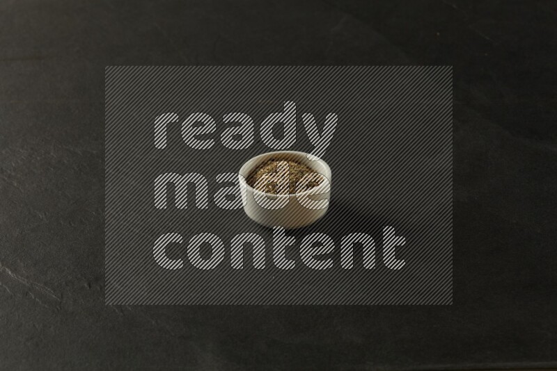 white ceramic round sauce bowl filled with herbs on grey textured countertop