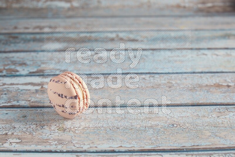 45º Shot of pink orange blossom macaron on light blue wooden background
