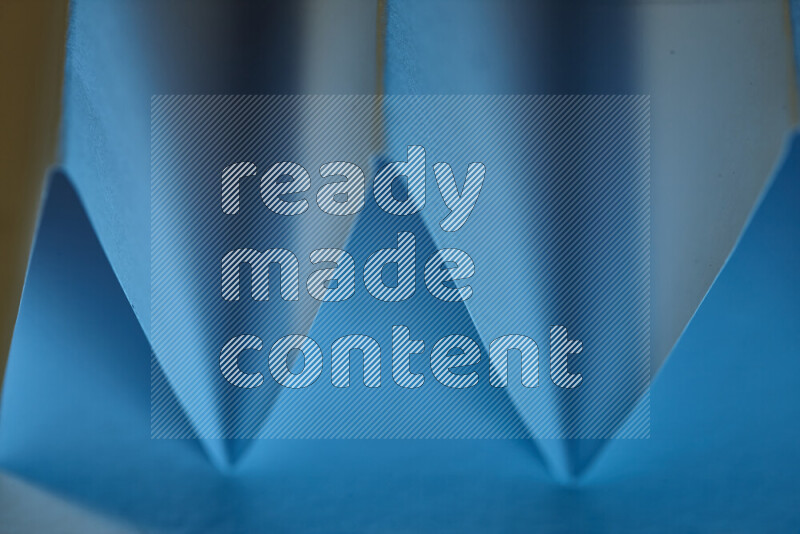 صورة مجردة مقربة تظهر طيات ورقية هندسية حادة بتدرجات اللون الأزرق