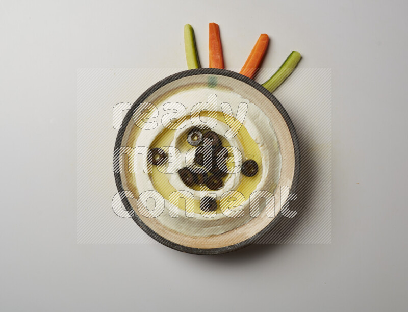 Lebnah garnished with sliced olives in a pottery plate on a white background